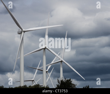 A group of wind mills or turbines under dark cloudy sky Stock Photo