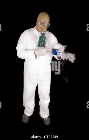 Man in hazard suit and wearing a gas mask, holding a glass container of blue chemical that is giving off a gas or steam, over a Stock Photo