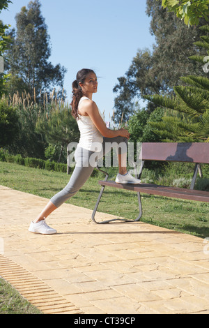 Runner stretching on park bench Stock Photo