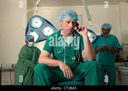 A surgeon using his mobile phone in between procedures. Stock Photo