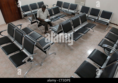 An patient sitting in an otherwise empty hospital waiting room. Stock Photo