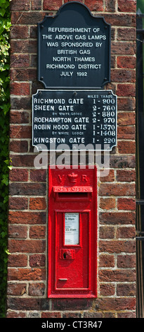 Old red post box and distance sign at the entrance to Ham Gate into Richmond Park in south west London Stock Photo