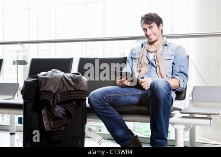Man using tablet computer in airport Stock Photo