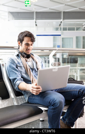 Man using laptop in airport waiting area Stock Photo