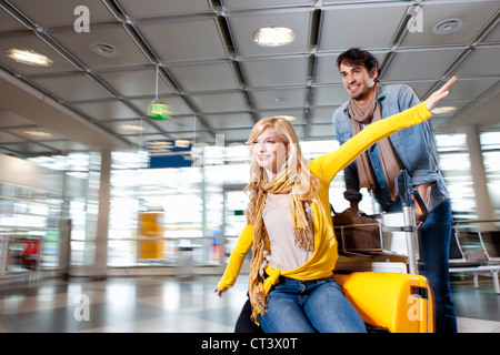 Couple playing with luggage in airport Stock Photo