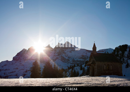 The morning sun rises over the Dents du Midi mountains illuminating the small chapel in Les Crosets, Switzerland. Stock Photo