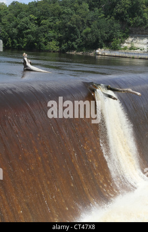 A tree trunk caught on the lip of the Ford dam on the Mississippi River in St. Paul, Minnesota. Stock Photo