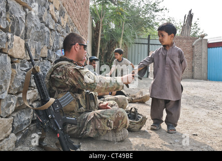 U.S. Army 1st Lt. Greg Lins, a native of Point Pleasant, N.J., and 3rd Platoon leader for A Battery, 2nd Battalion (Airborne), 377th Parachute Field Artillery Regiment, greets a local Afghan boy inside a qalat of a female school in the village of Mangas July 7, 2012. Paratroopers of Task Force 2-377 pulled security in and around the school while members of the female engagement team spoke with teachers of the school to discuss concerns about the schools future. Stock Photo