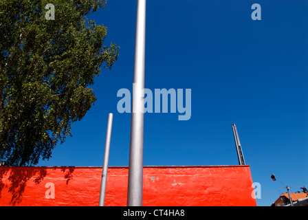 RED WALL BEHIND METAL POLES Stock Photo
