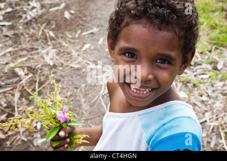 Indonesia, Papua New Guinea, Fergusson Island. Close-up shot of young boy holding flowers. Stock Photo