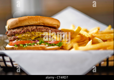 A cheeseburger in a basket with french fries. Stock Photo