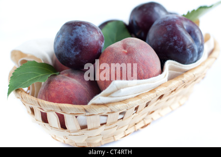 Ripe peaches and plums in the basket, closeup Stock Photo