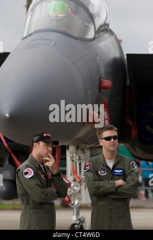 Two US Air Force crew stand below the nose of their F-16C fighter jet at the Farnborough Air Show, UK. Stock Photo