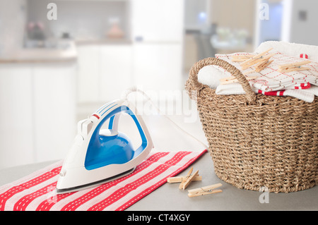 Laundry on ironing board in kitchen setting Stock Photo