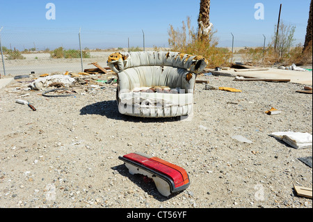 Abandoned upholstered chair, Salton Sea Beach, California USA Chair with car brake light in foreground, chain link fence behind. Stock Photo