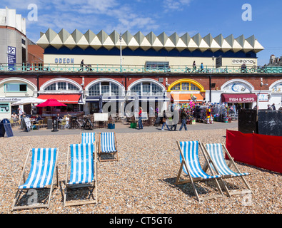 Odeon Cinema and Oceana Nightclub on Brighton seafront and in the foreground empty deck chairs and bars on the lower promenade Stock Photo