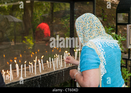 Woman lighting candles outside the House of the Virgin Mary, Meryemana, near Ephesus and Selcuk, Turkey Stock Photo