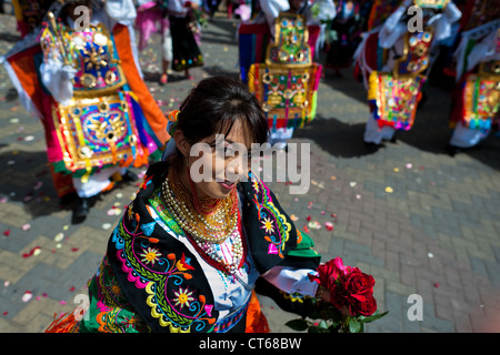 A dancer (danzante), holding flowers, performs in the religious parade within the Corpus Christi festival in Pujilí, Ecuador. Stock Photo