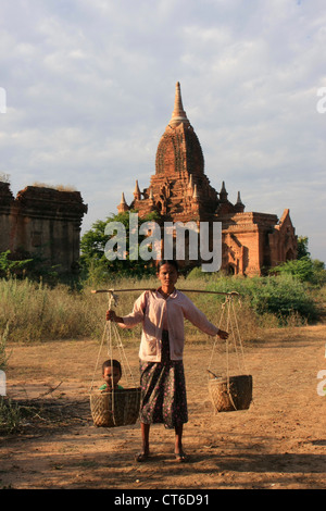 Local burmese woman carrying child in basket, Bagan Archaeological Zone, Mandalay region, Myanmar, Southeast Asia Stock Photo