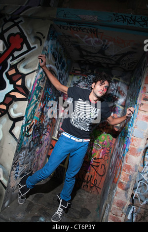 Stylish young man posing against graffiti on wall Stock Photo