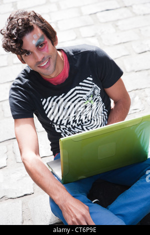 Portrait of a happy young man using laptop outdoors Stock Photo
