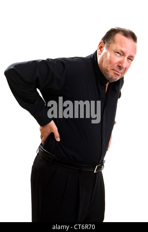 Elderly man holds his back and bends over in pain and makes a grimacing facial expression. Stock Photo