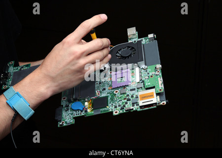 Closeup of computer motherboard being repaired by technician, on black background. Stock Photo