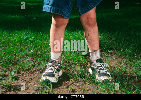 A close up of a boys dirty knees from playing sports in the rain. Stock Photo