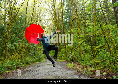 Jumping woman in forest with red umbrella