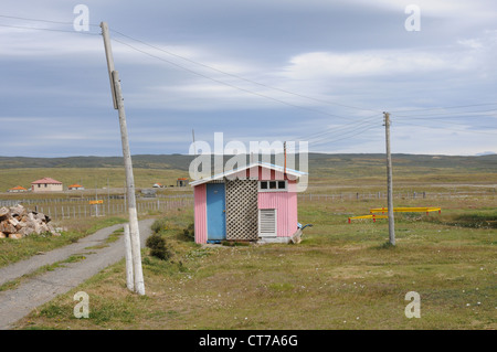 Pink hut with blue door, telegraph poles, wide empty landscape, Patagonia. Stock Photo