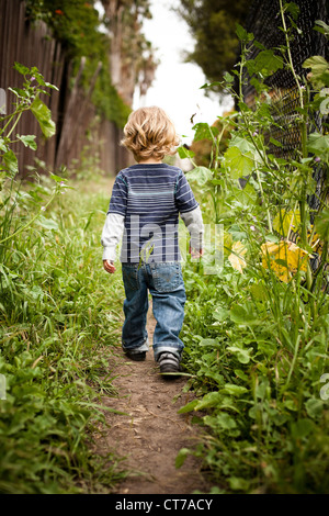 Boy walking on dirt track rear view Stock Photo