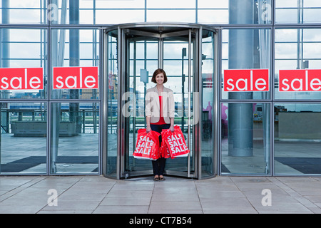 Woman in shop doorway with sale bags Stock Photo