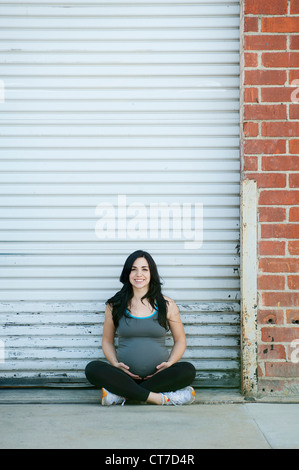 Pregnant young woman sitting cross legged, portrait Stock Photo