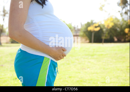 Pregnant young woman touching stomach, side view Stock Photo