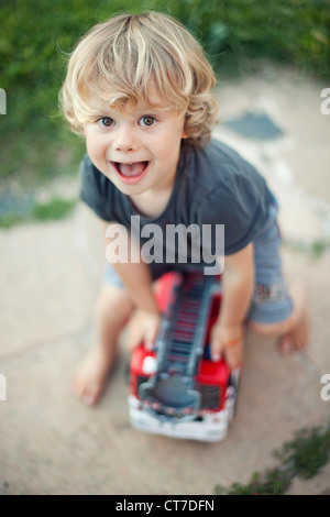 Boy playing with toy fire engine Stock Photo