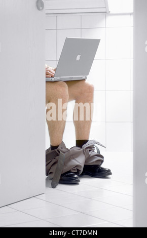Man with laptop on the toilet Stock Photo