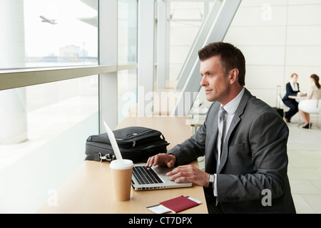 Businessman using laptop in airport Stock Photo