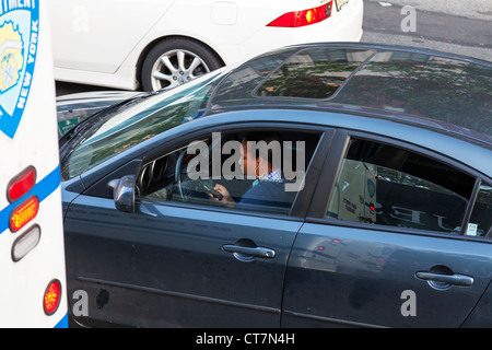 Woman lady driver using mobile phone whilst driving her car in traffic in New York City Stock Photo