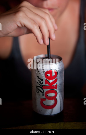 A woman drinks a can of Diet Coke through a straw Stock Photo