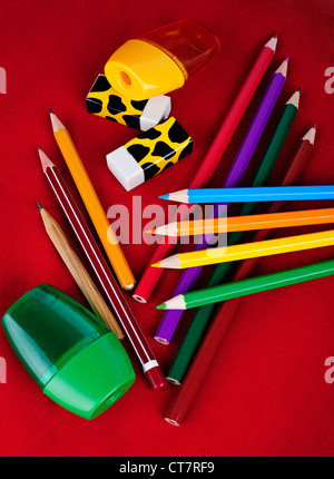 Colored pencils, erasers, sharpeners isolated on red background Stock Photo