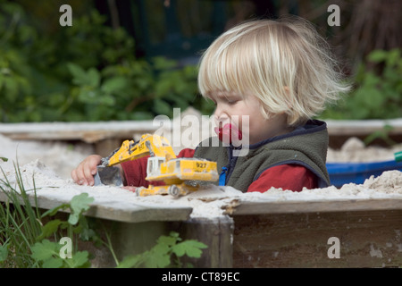 A toddler playing in sandbox Stock Photo