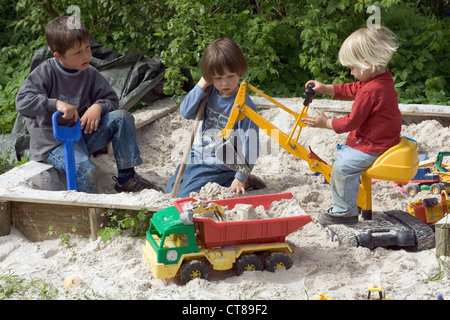 Three children playing in the sandbox Stock Photo