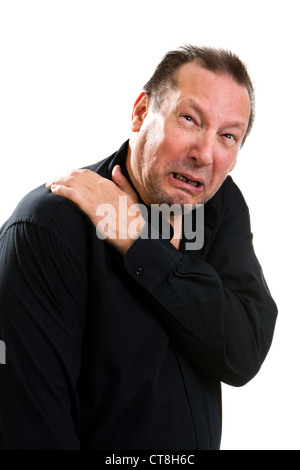 Elderly man suffering with a hurting shoulder rubs it with his hand and makes a painful expression. Stock Photo