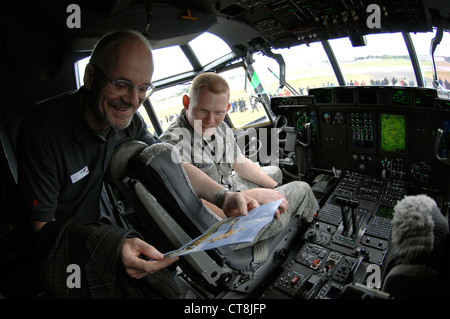 U.S. Air Force Senior Airman Eric Cobaugh, 86th Aircraft Maintenance Squadron crew chief, reviews a pamphlet with Helmut Frisch of 3M Energy and Advance Materials Division in the cockpit of a C-130 J Super Hercules July 9, 2012, during the Farnborough International Air Show in Farnborough, England. Approximately 90 aircrew and support personnel from bases in Europe and the United States are participating in the air show. The world renowned event exhibits the latest in aerospace equipment and technology. Stock Photo