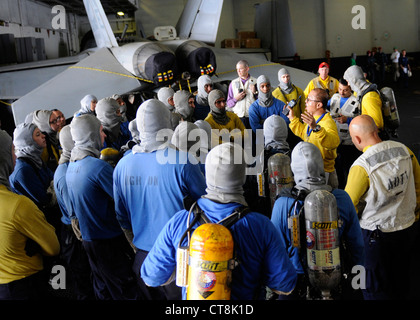 Sailors gather in the hangar bay of the Nimitz-class aircraft carrier USS Abraham Lincoln (CVN 72) for firefighting training during a general quarters drill. Lincoln is deployed to the U.S. 5th Fleet area of responsibility conducting maritime security operations, theater security cooperation efforts and combat flight operations in support of Operation Enduring Freedom. Stock Photo