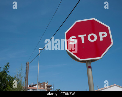 red stop sign against a clear blue sky with street furniture and cables in Spain Stock Photo