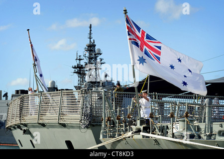 Australian sailors raise the colors aboard the Royal Australian navy Adelaide-class guided-missile frigate HMAS Darwin (FFG 04) and the Royal Australian navy Anzac-class frigate HMAS Perth (FFH 157) during Rim of the Pacific (RIMPAC) 2012. Twenty-two nations, 42 ships, six submarines, more than 200 aircraft and 25,000 personnel will participate in the biennial Rim of the Pacific (RIMPAC) 2012 exercise scheduled June 29 to Aug. 3, in and around the Hawaiian Islands. RIMPAC is the world's largest international maritime exercise Stock Photo