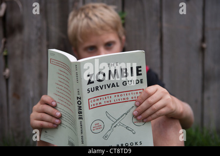 Ten year old boy reading The Zombie Survival Guide. Stock Photo
