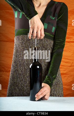 woman opening a red wine bottle with corkscrew Stock Photo