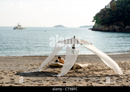 Couple relaxing on the beach at l'Eco del Mare hotel part-owned by Italian singer Zucchero Lerici Tuscany Italy Stock Photo